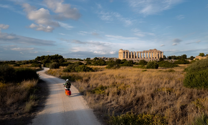 A man riding a scooter on a country road in an unnamed destination