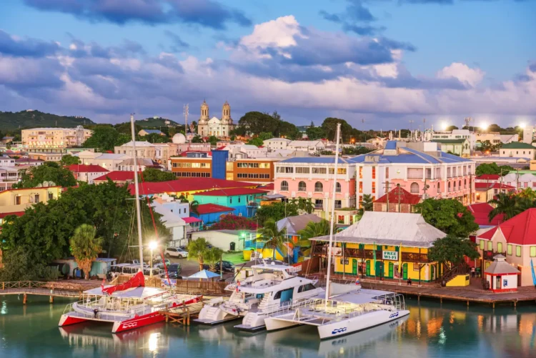 Waterfront view of St. John’s, Antigua at dusk with colorful buildings and boats along the quay.