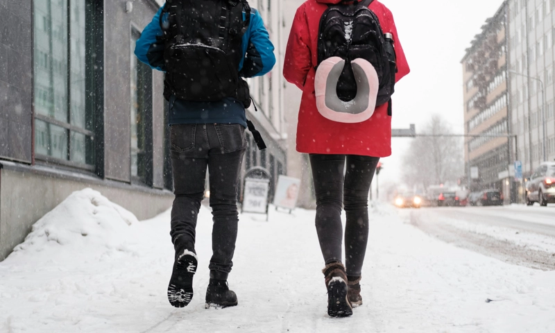 A couple of people walking down a snow covered street