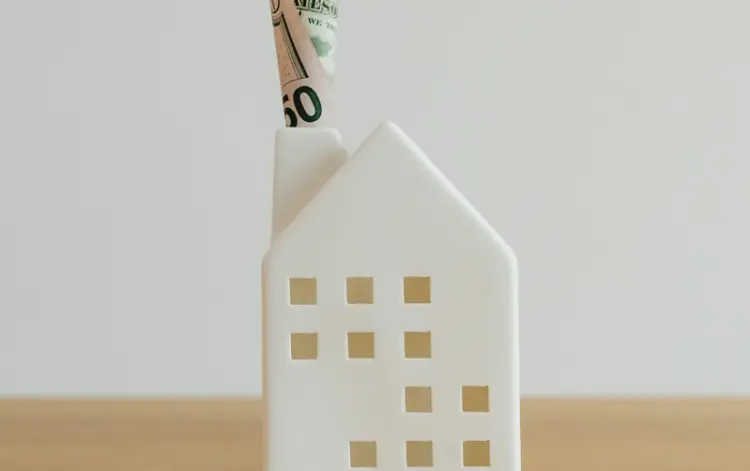A house-shaped money holder on a wooden table.