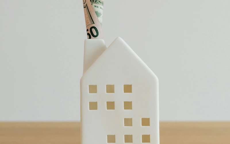 A house-shaped money holder on a wooden table.