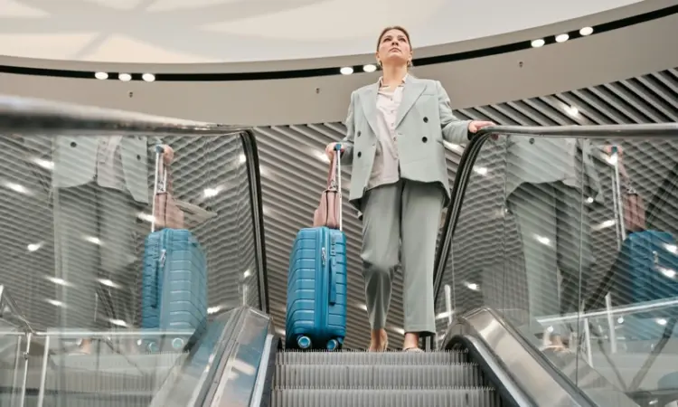 A woman on top of an escalator with luggage