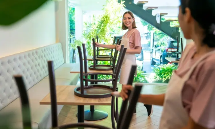 Restaurant employees stacking chairs