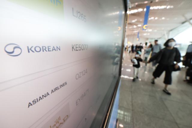 Flight information boards at Incheon International Airport Terminal 2 show Korean Air and Asiana Airlines listings.