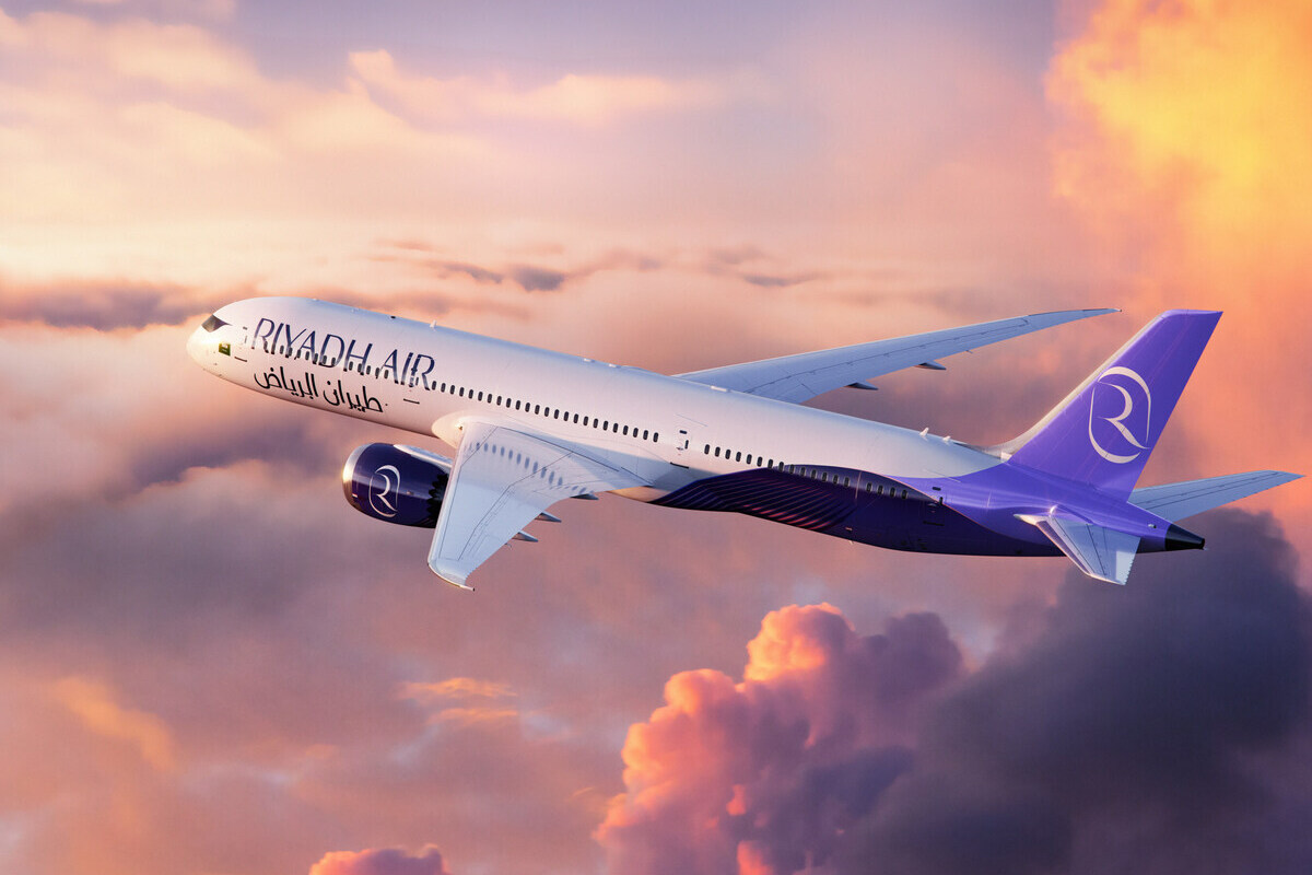 A Riyadh Air 787 in flight above cloud at sunset