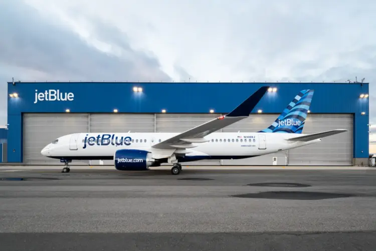 JetBlue Airbus A220-300 aircraft parked in front of blue hangar at airport