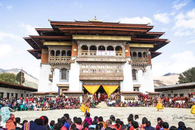 Scenic view of a traditional bhutanese monastery perched on a lush green himalayan mountainside under a clear blue sky.