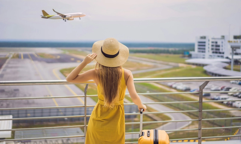 A woman at an airport watching an airplane land