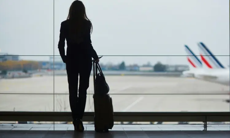 A woman in an airport terminal looking at airplanes
