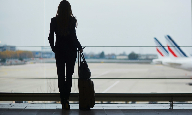 A woman in an airport terminal looking at airplanes