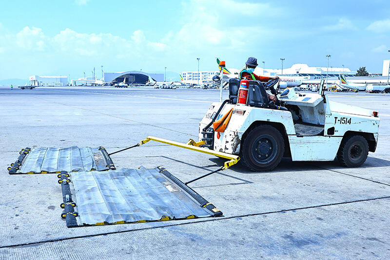 Staff member on a vehicle removing FOD from the apron