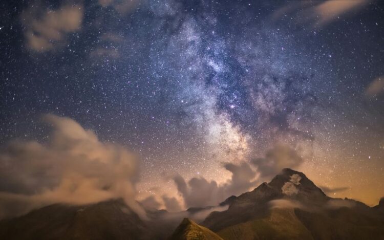 A high-resolution view of the milky way galaxy stretching over the silhouette of traditional bhutanese architecture and mountain peaks in punakha.