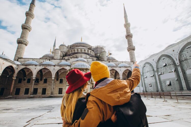 A young European couple walks in the courtyard of the Blue Mosque in Istanbul, Türkiye. (Adobe Stock Photo)