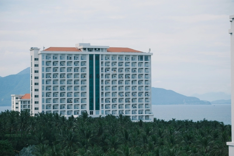 Large white hotel building overlooking the ocean.