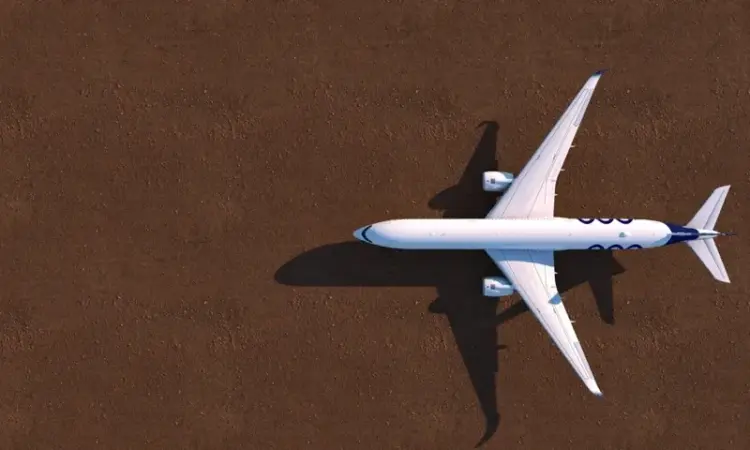A white airplane flying over a brown ground