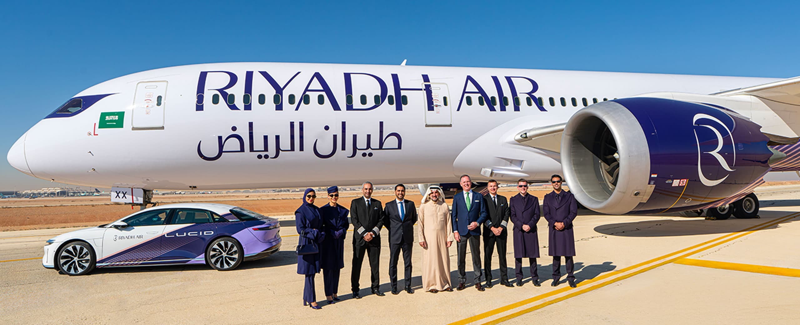 A Riyadh Air aircraft in the sun with people in front of it