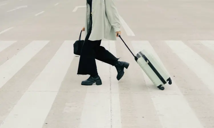 A person pulling luggage crossing a street