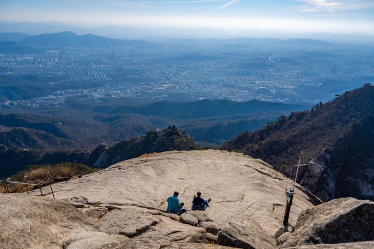 Hikers sit on a rock at Baegundae Peak of Mount Bukhan in Seoul, Feb. 26. Courtesy of Seoul Tourism Organization