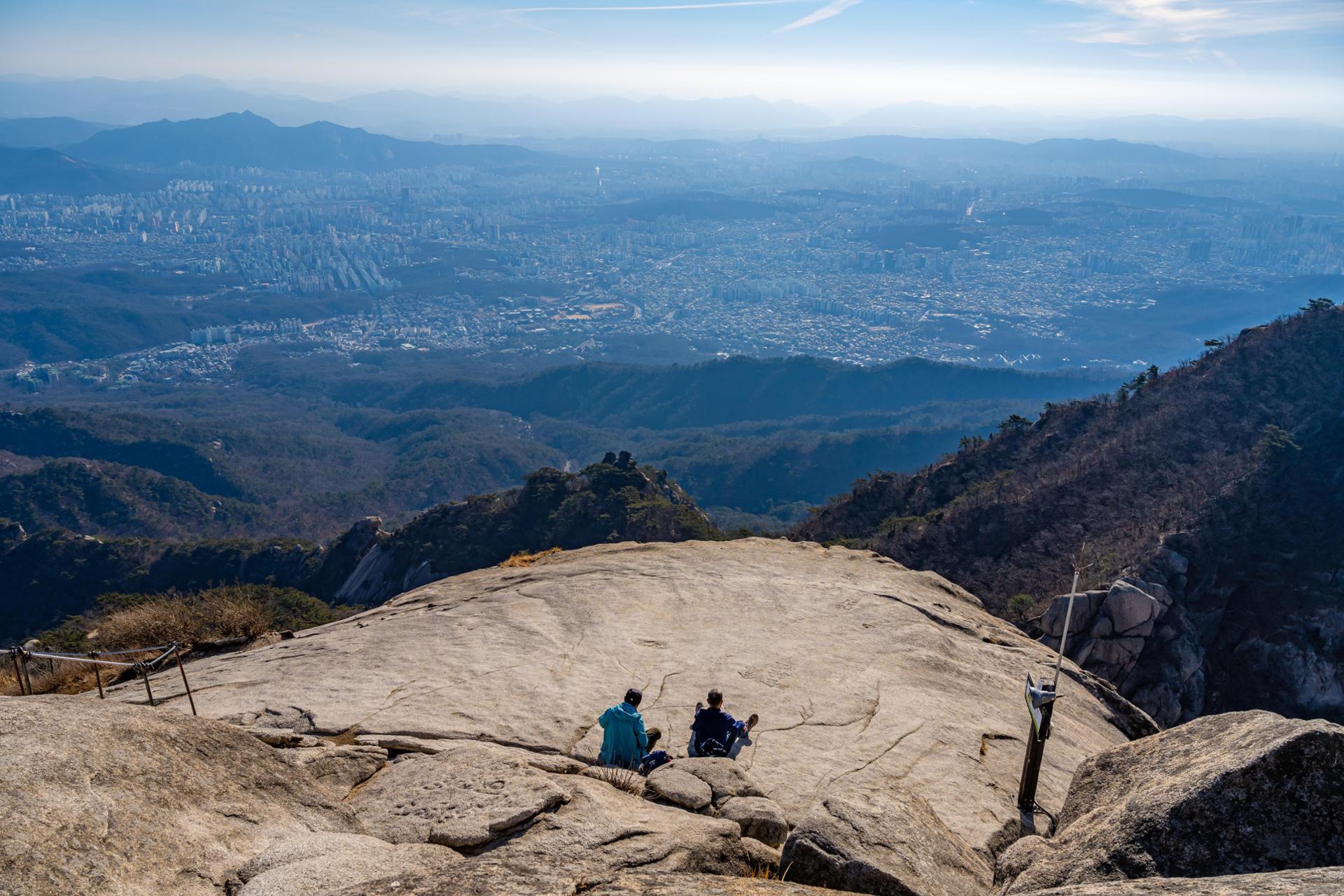 Hikers sit on a rock at Baegundae Peak of Mount Bukhan in Seoul, Feb. 26. Courtesy of Seoul Tourism Organization