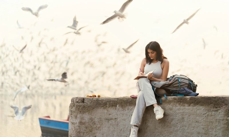 A woman sitting on a wall and looking at her phone