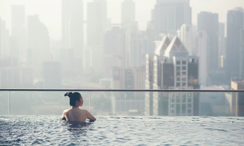 A woman in an infinity pool overlooking a city.