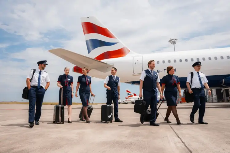 British Airways cabin crew and pilots walking beside aircraft on airport runway