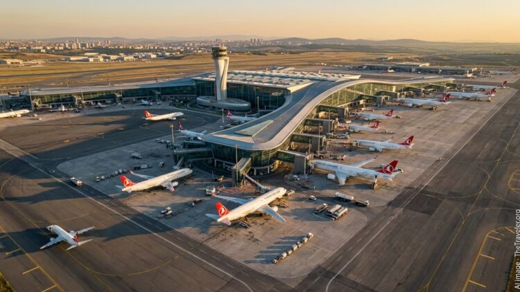 Aerial view of Istanbul Airport at golden hour with terminals, runways and Turkish Airlines jets.
