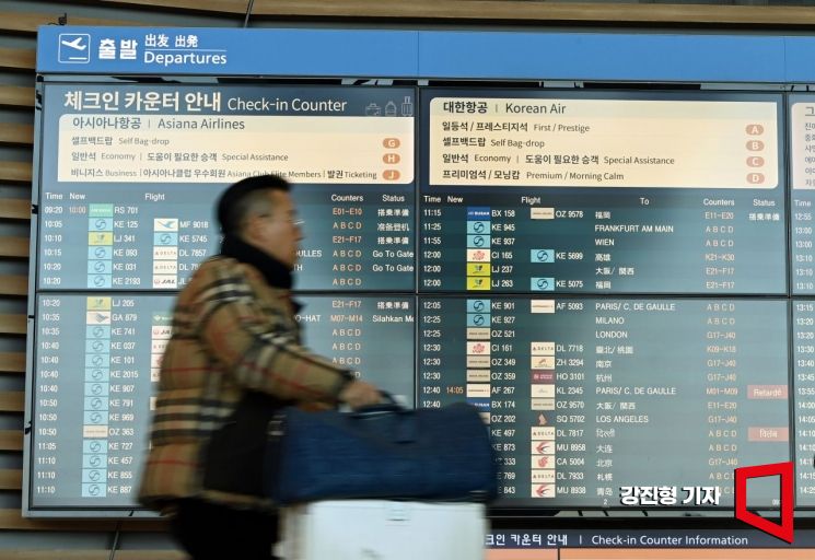Passengers are passing in front of the terminal digital display at Incheon International Airport. Photo by Jinhyung Kang