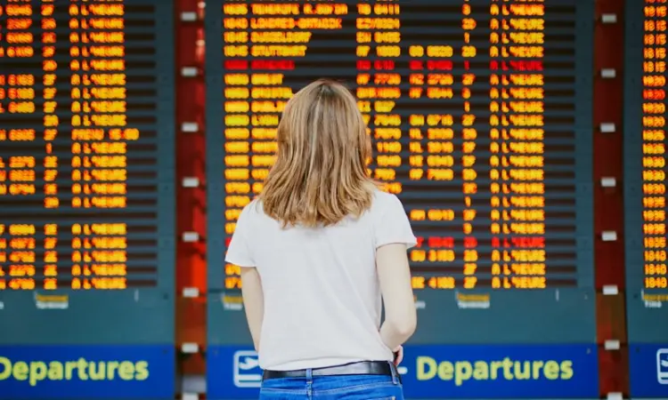 A woman in front of an airport departure board