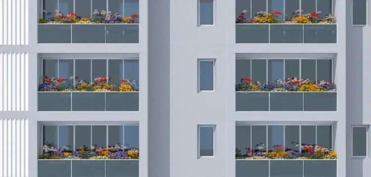 A modern building with several units, each featuring glass-railed balconies filled with vibrant flowers.