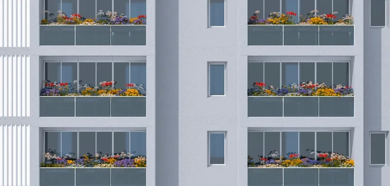 A modern building with several units, each featuring glass-railed balconies filled with vibrant flowers.