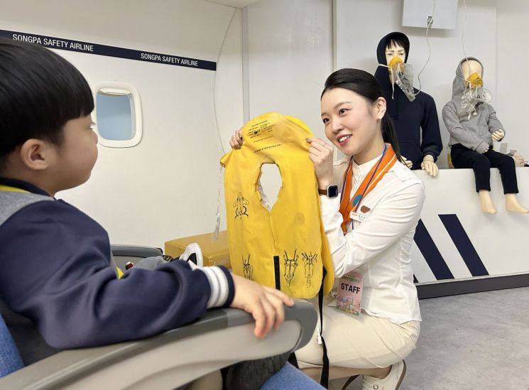 A Jeju Air flight attendant is teaching how to wear a life jacket in an emergency situation at the
