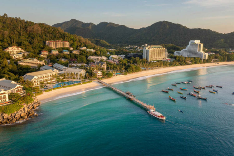 Aerial view of phuket's coastline with luxury resorts and boats in the turquoise.