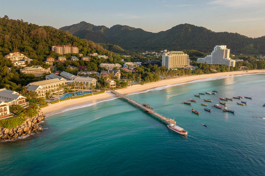 Aerial view of phuket's coastline with luxury resorts and boats in the turquoise.