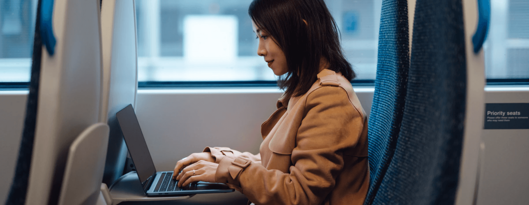 Image of lady on public transport on her laptop