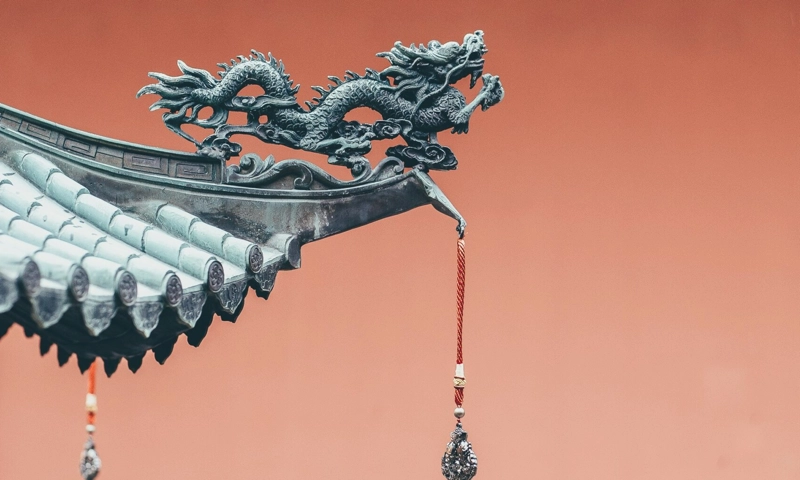 a detailed, stylized dragon sculpture perched on the upturned eave