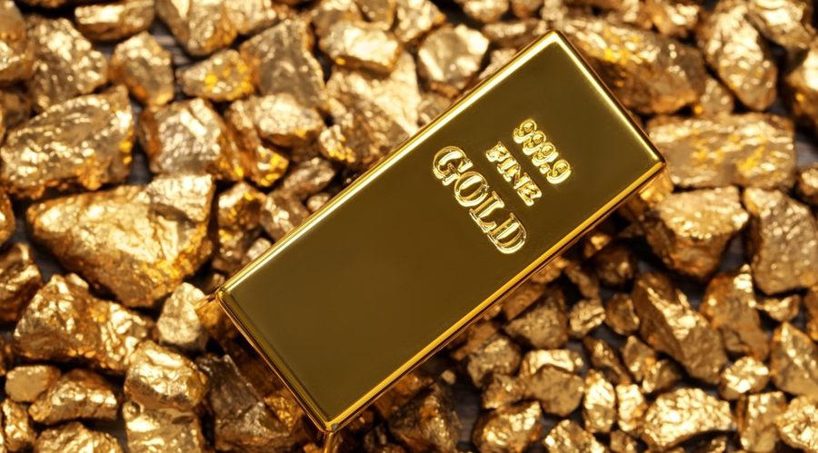 Gold bar laying on gold nuggets.