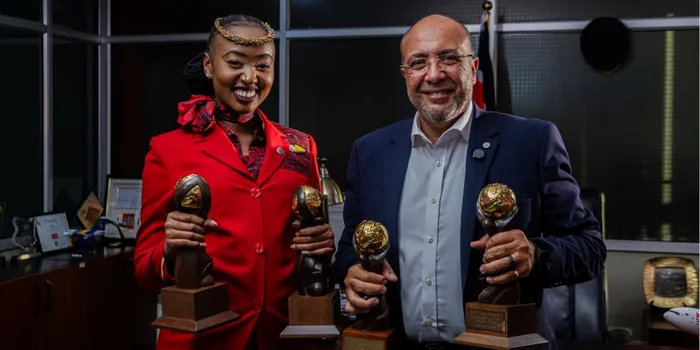 Kenya Airways Acting CEO George Kamal and an air hostess holding the various 2026 World Travel Awards won by KQ.
