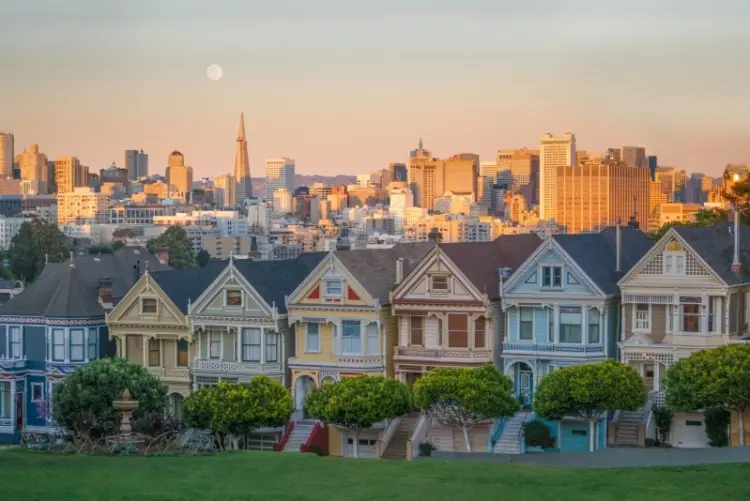The Painted Ladies houses in San Francisco with the city skyline at low sun