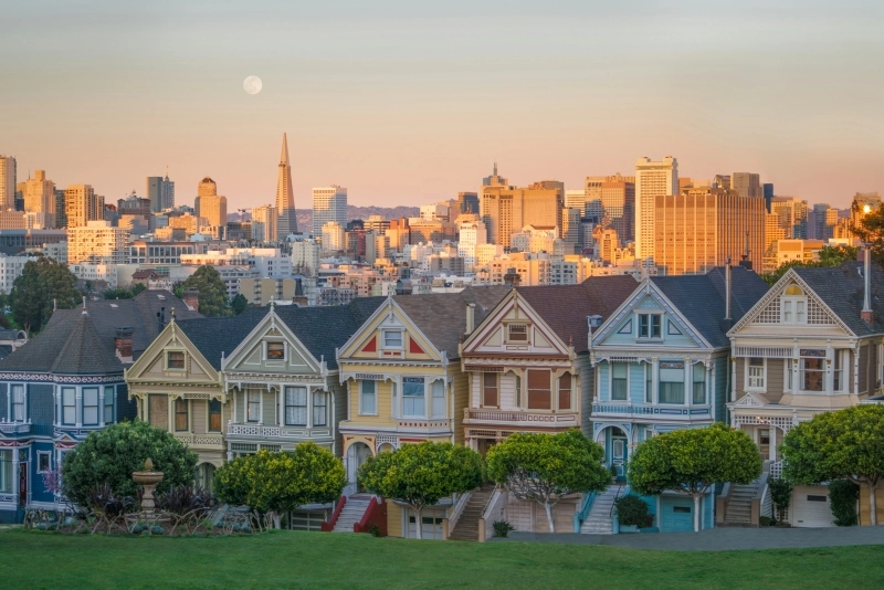 The Painted Ladies houses in San Francisco with the city skyline at low sun