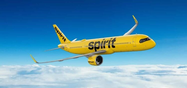 Spirit airlines plane in flight above clouds, disrupting travel plans.